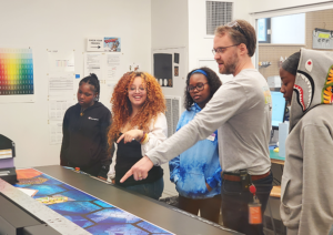 Educator and students watch printing process