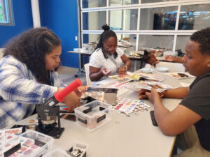 Three people work on button making