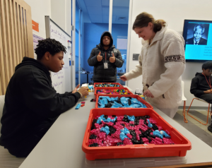 Three people work with electronic blocks