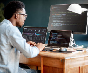 Student works on computer with three monitors