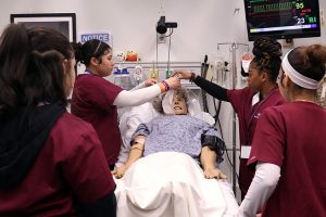 Health Assisting students work with dummy patient