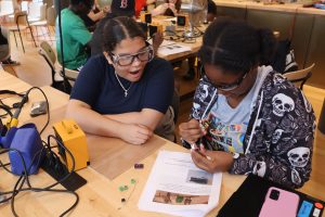 Two HS students solder a circuit board