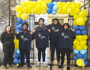 four high school students display college t-shirts after receiving onsite admission